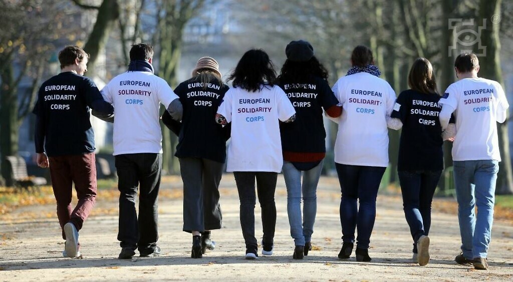 Zdjęcie przedstawiające członków Europejskiego Korpusu Solidarności widocznych od tyłu w scenerii parkowej alejki.